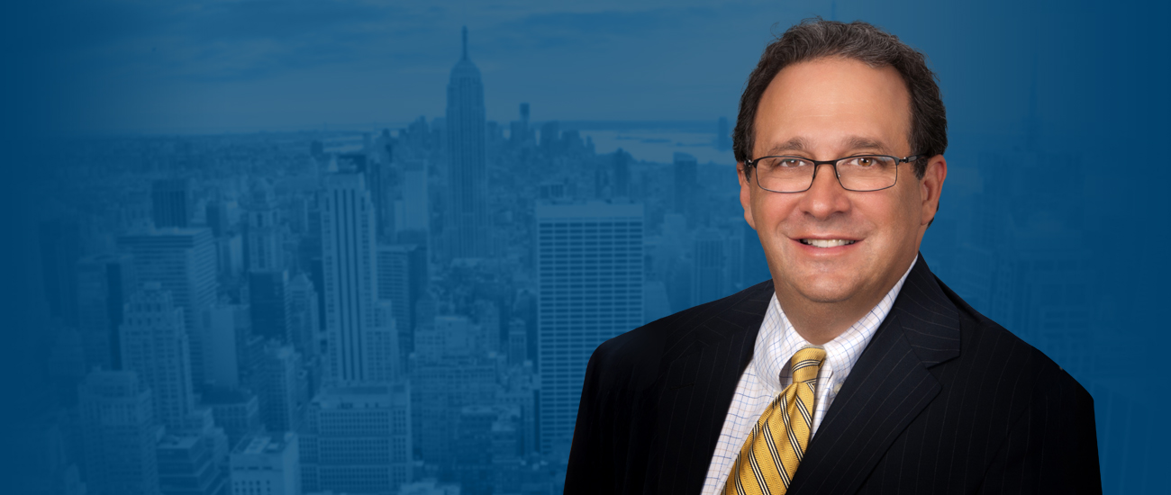 Stephen Bilkis against a blue-tinted cityscape background featuring the Empire State Building.